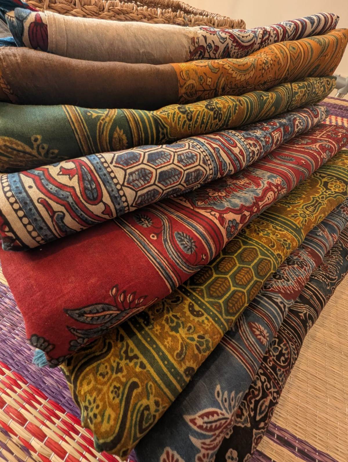 a stack of beautiful ajrakh chanderi sarees