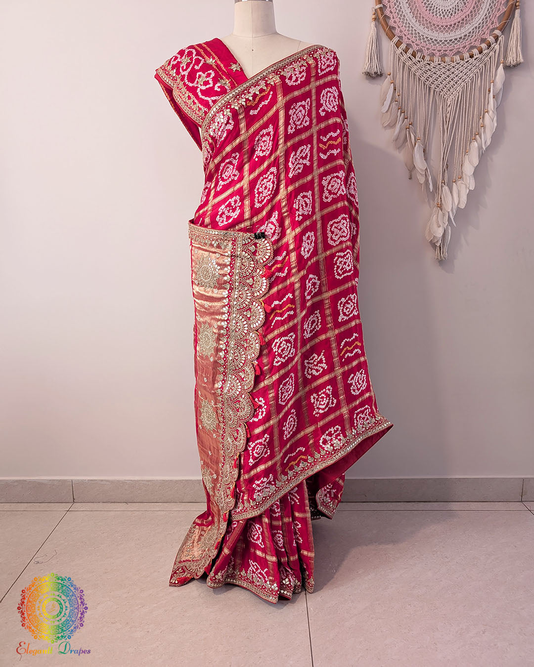 Red and white patterned saree with gold border on a mannequin against a plain background