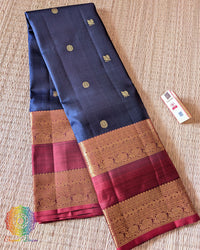 Folded navy blue Kanjivaram silk saree showing red border and 2 gram zari weaving