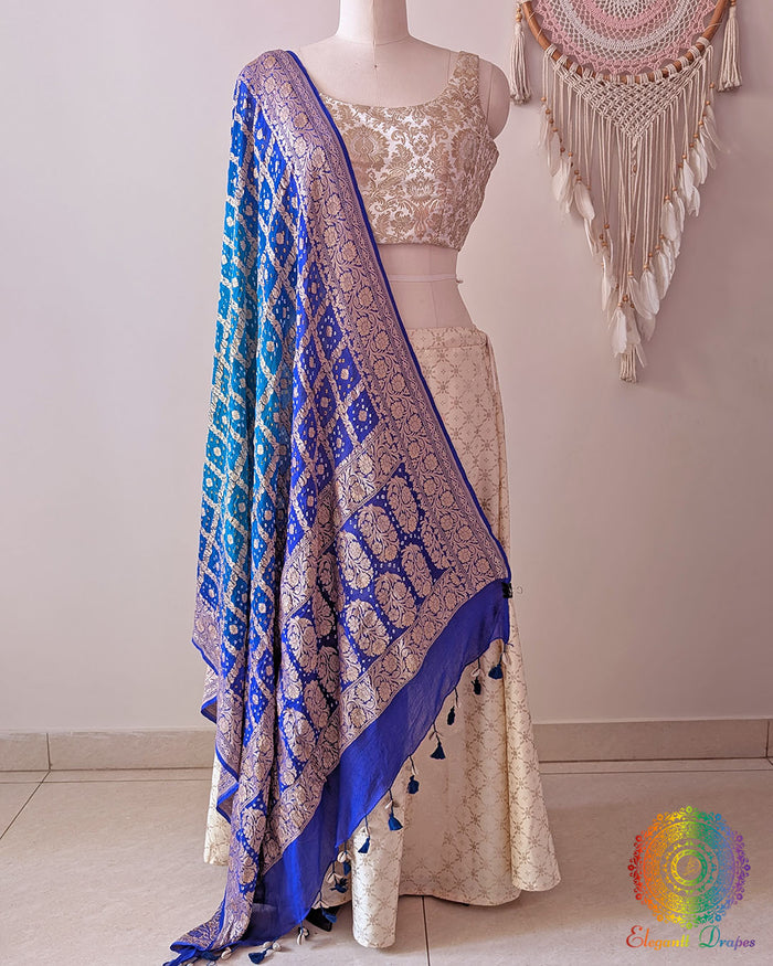 Blue shaded Banarasi georgette Gharchola Bandhani dupatta draped on mannequin with zari border and kodi tassels