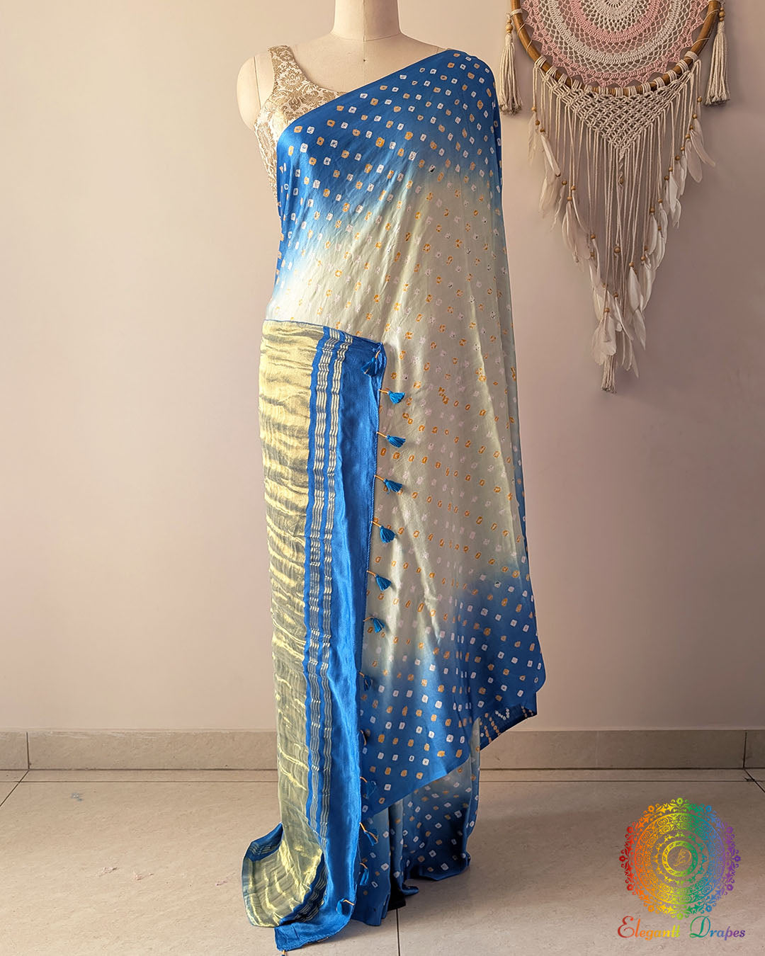Blue shaded gaji silk saree on mannequin showcasing traditional bandhani dots