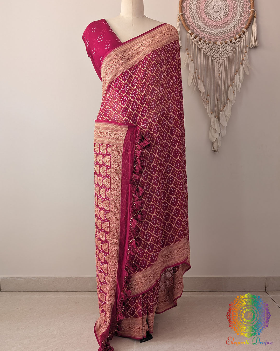 Deep magenta Khaddi georgette Banarasi Bandhani saree on mannequin showing full drape and handcrafted tassels