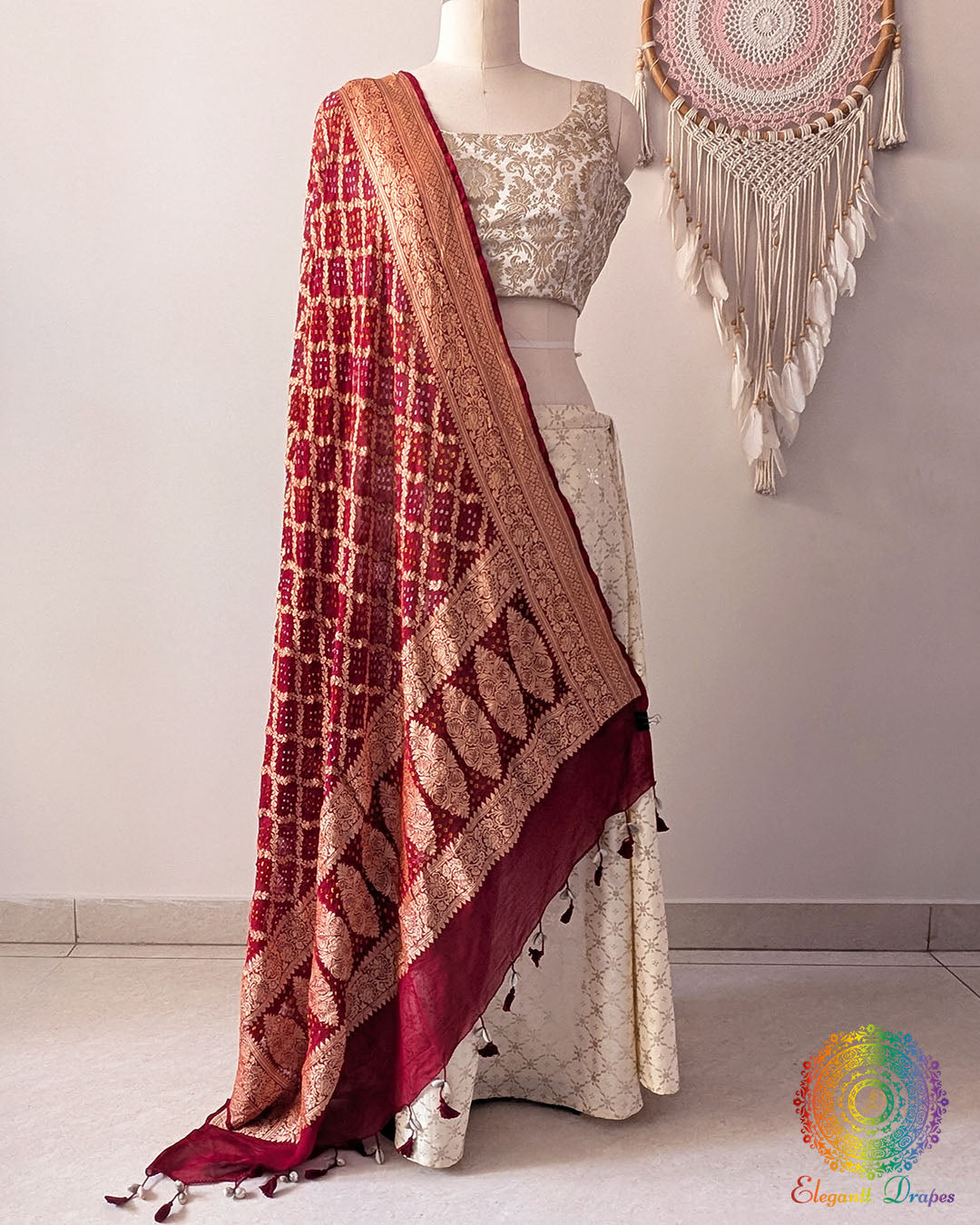 Deep red Banarasi georgette Gharchola Bandhani dupatta draped on mannequin with zari border and kodi tassels