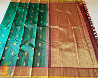 Full green Kanjivaram silk saree laid open showing red palla and woven design