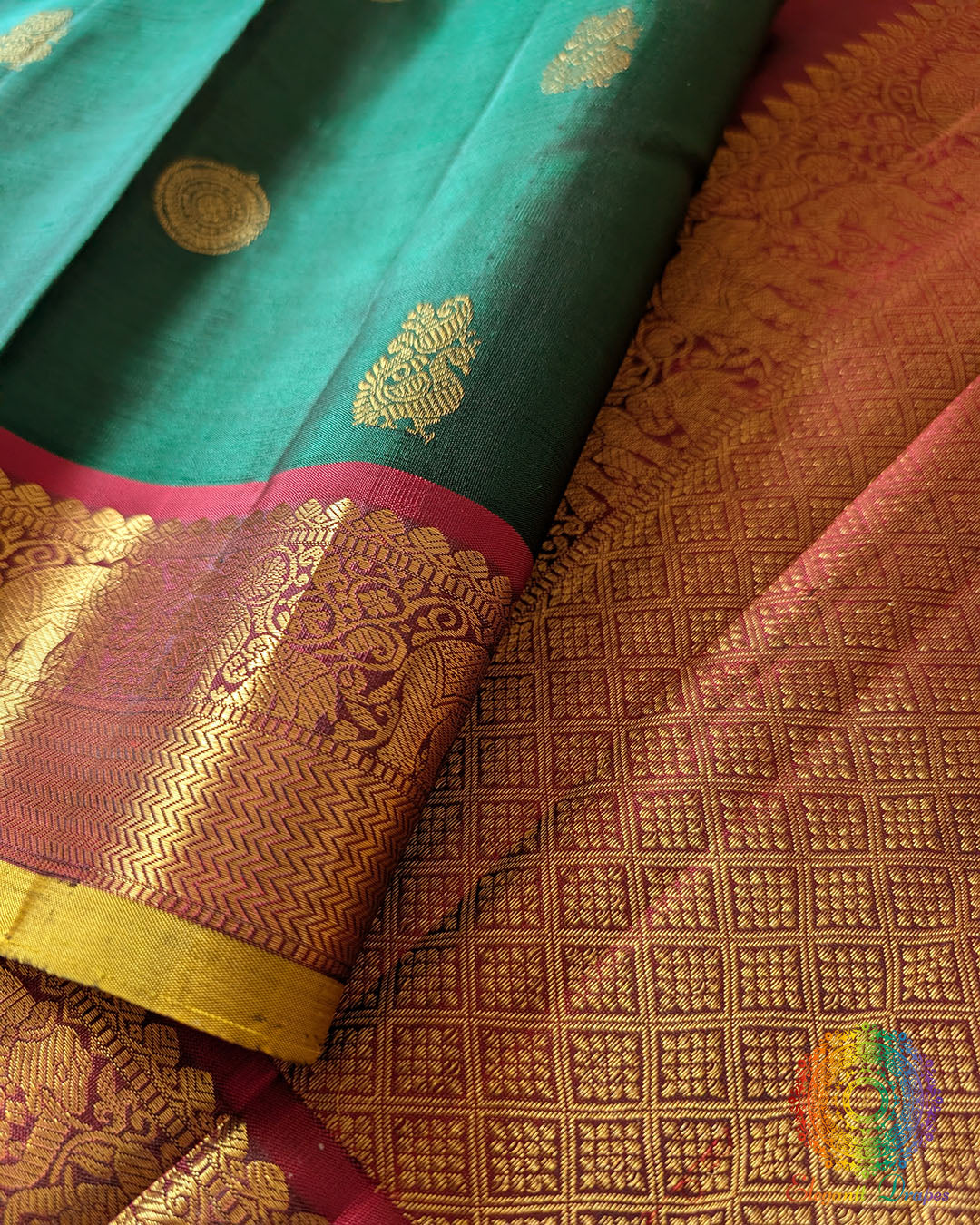 Red border close up on green Kanjivaram silk saree highlighting zari weaving