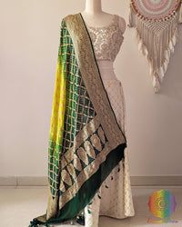 Green shaded Banarasi georgette Gharchola Bandhani dupatta draped on mannequin with zari border and kodi tassels