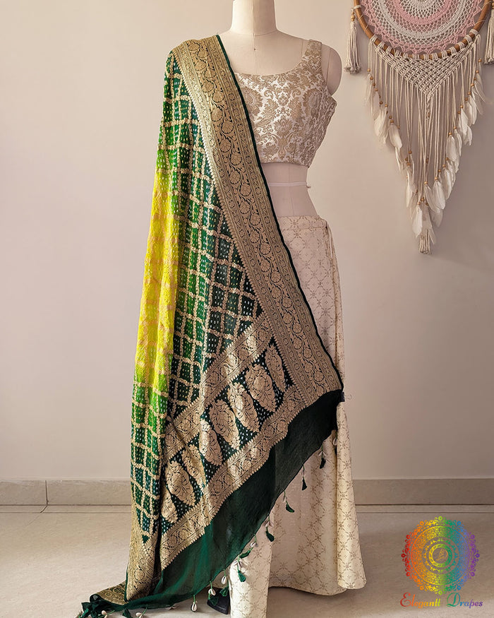 Green shaded Banarasi georgette Gharchola Bandhani dupatta draped on mannequin with zari border and kodi tassels