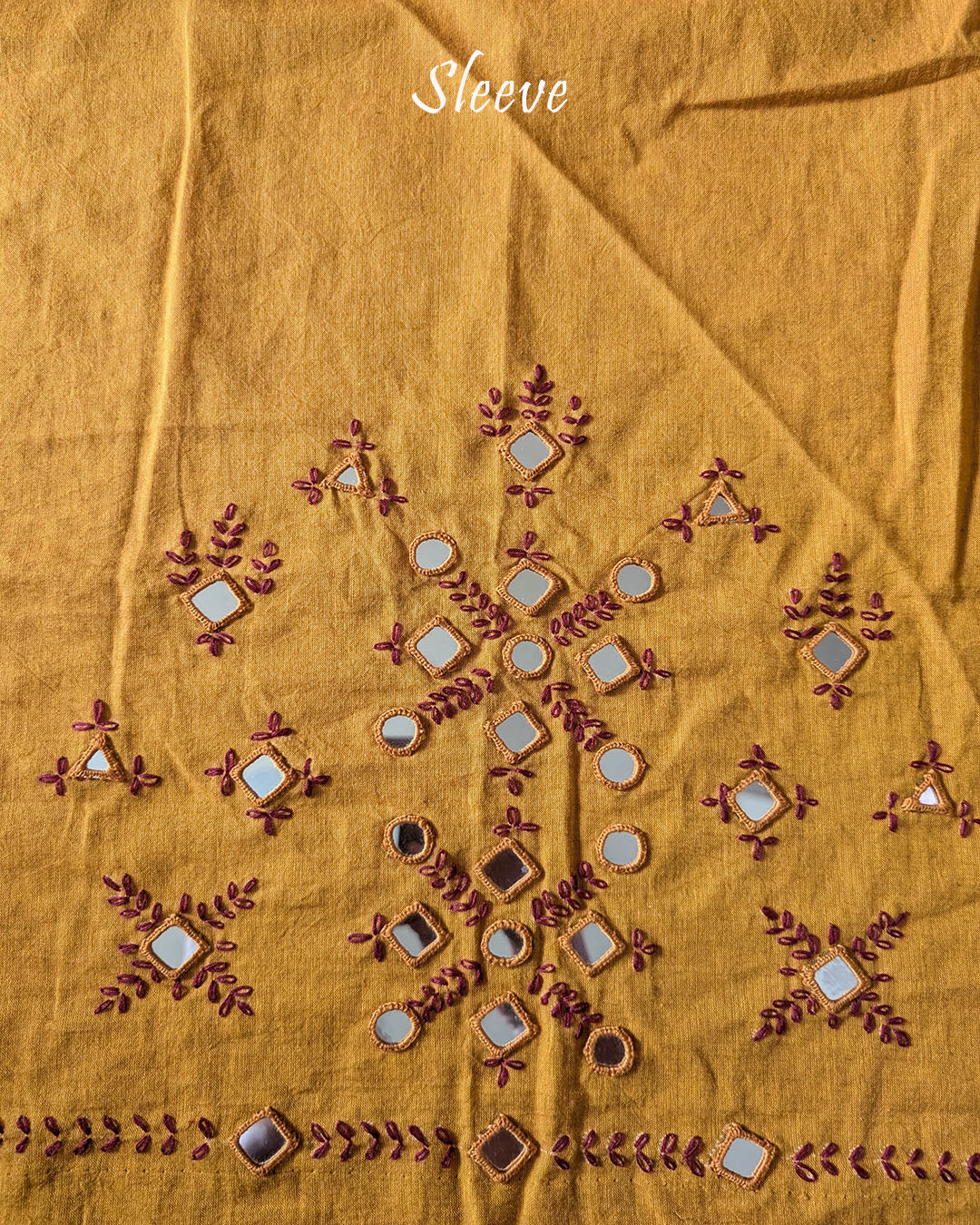 Sleeve detail of the Mustard Kala Cotton Kutch Mirror Handwork blouse piece, highlighting the real mirror embellishments, intricate threadwork and warm mustard cotton fabric.