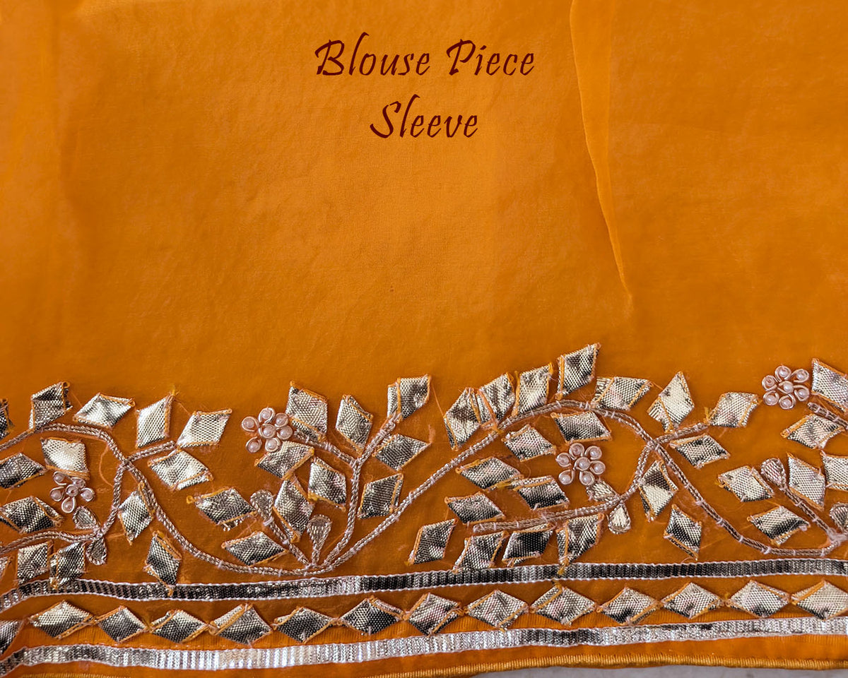 Mustard Orange Organza Leheria Saree – Blouse sleeve detail showcasing the matching fabric and handcrafted Kachha Gota embellishment