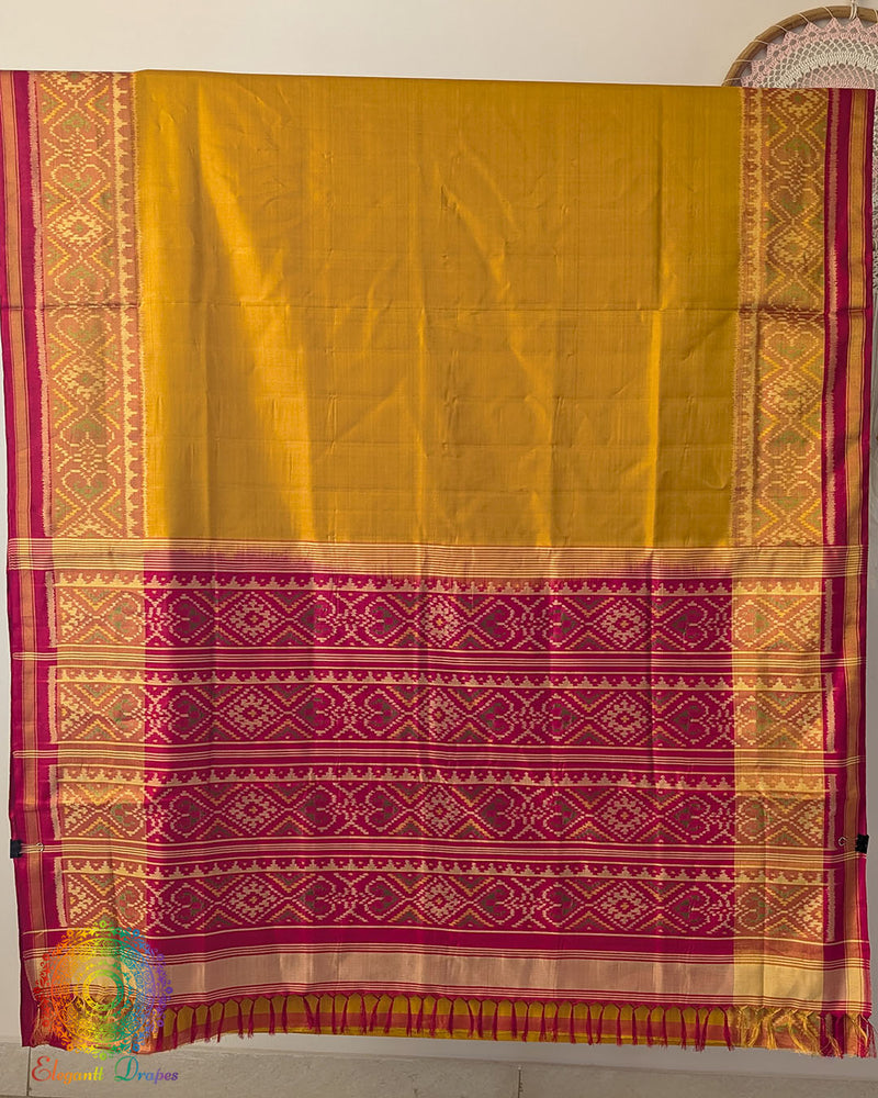 Open palla view of mustard Rajkot Patola pure mulberry silk saree displaying red palla and woven design