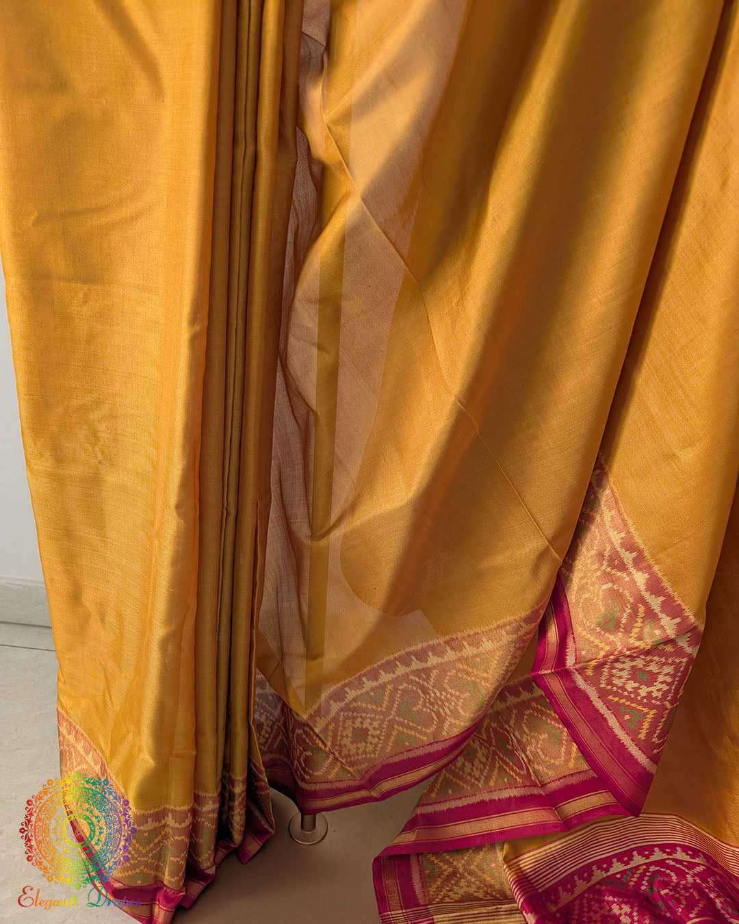 Pleats close up on mustard Patola silk saree showcasing traditional weave and pattern