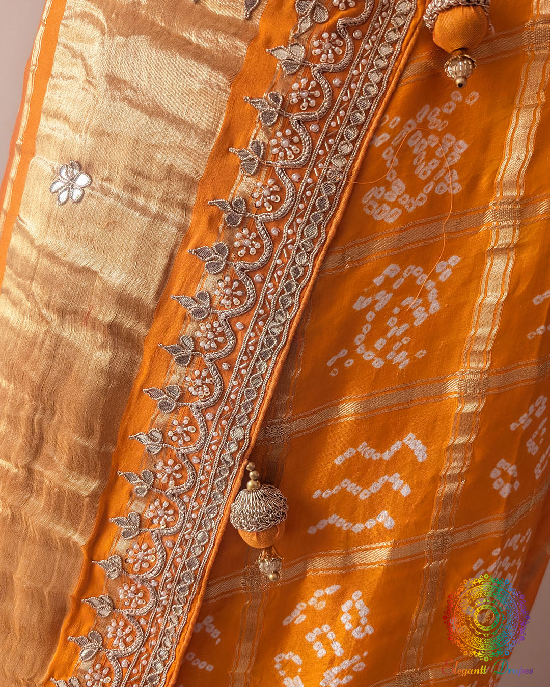Detailed view of handcrafted gota patti embellishment on orange Gharchola saree