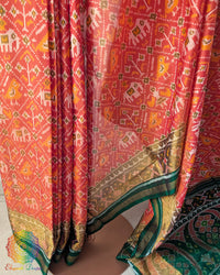 Pleats close up on orange Patola silk saree showcasing traditional weave and pattern