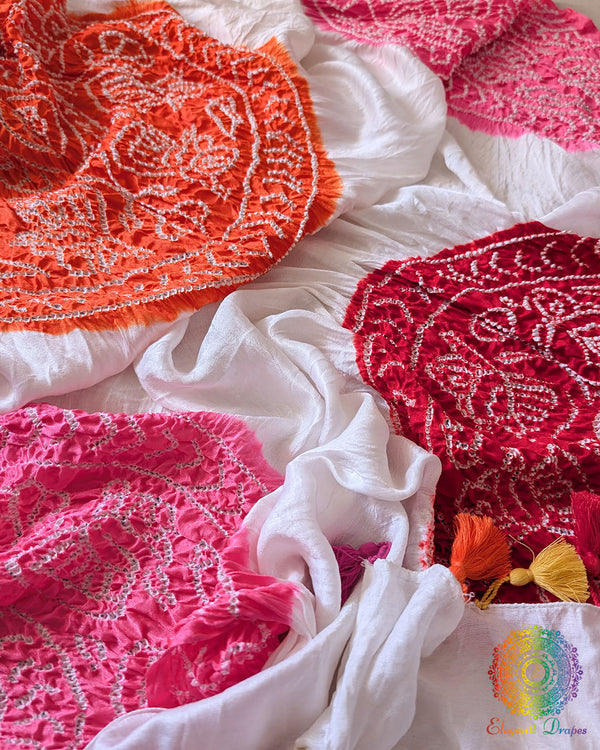 White Gajji Silk Multicolour Bandhani Dupatta, highlighting the colourful arrangement of orange, pink, red and yellow patterns against the white silk fabric.