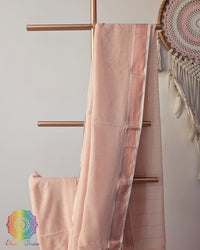 Pale peach Bengal cotton saree body close up highlighting fabric texture with zari border detail