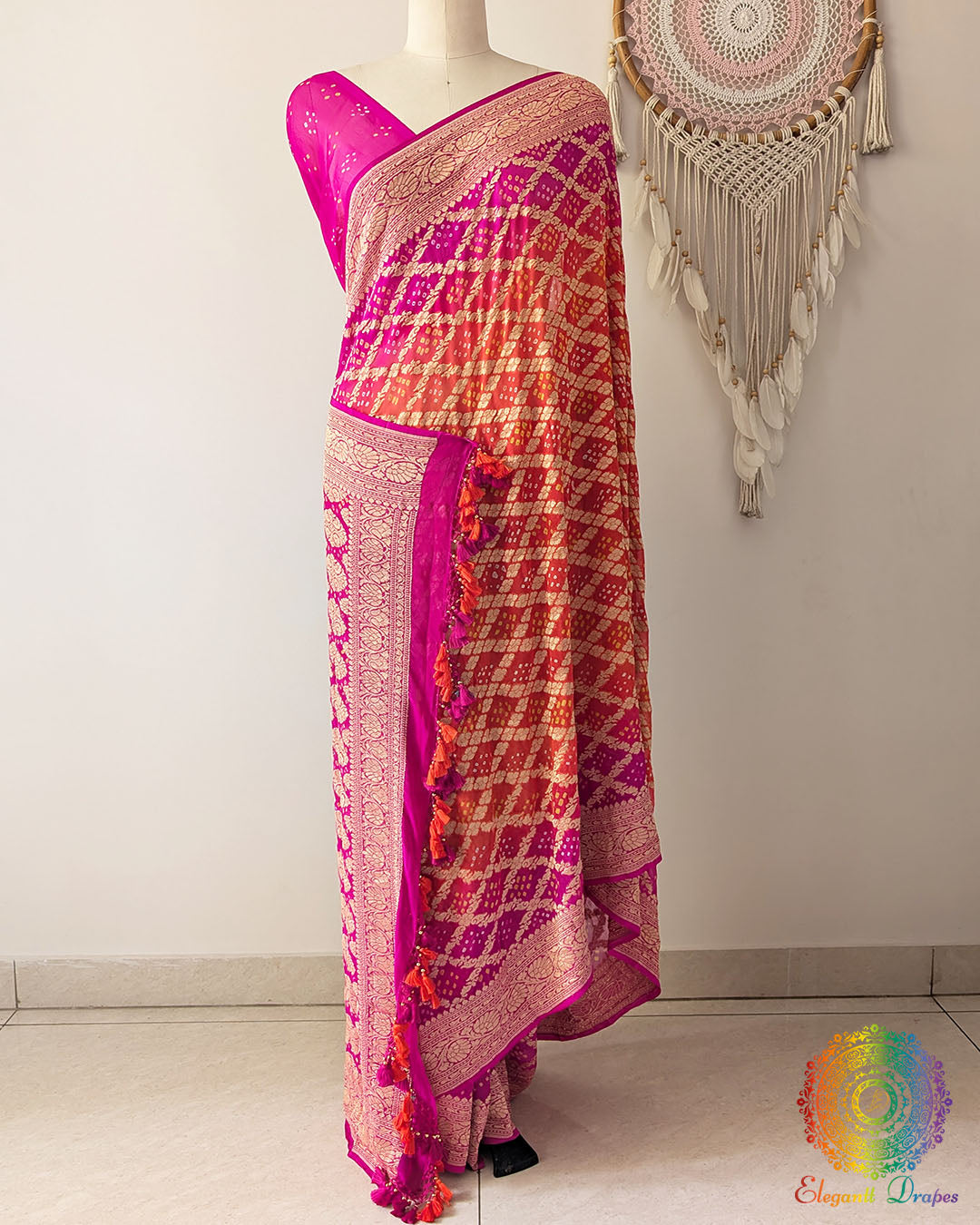 Pink orange shaded Khaddi georgette Banarasi Bandhani saree on mannequin showing full drape and handcrafted heavy tassels