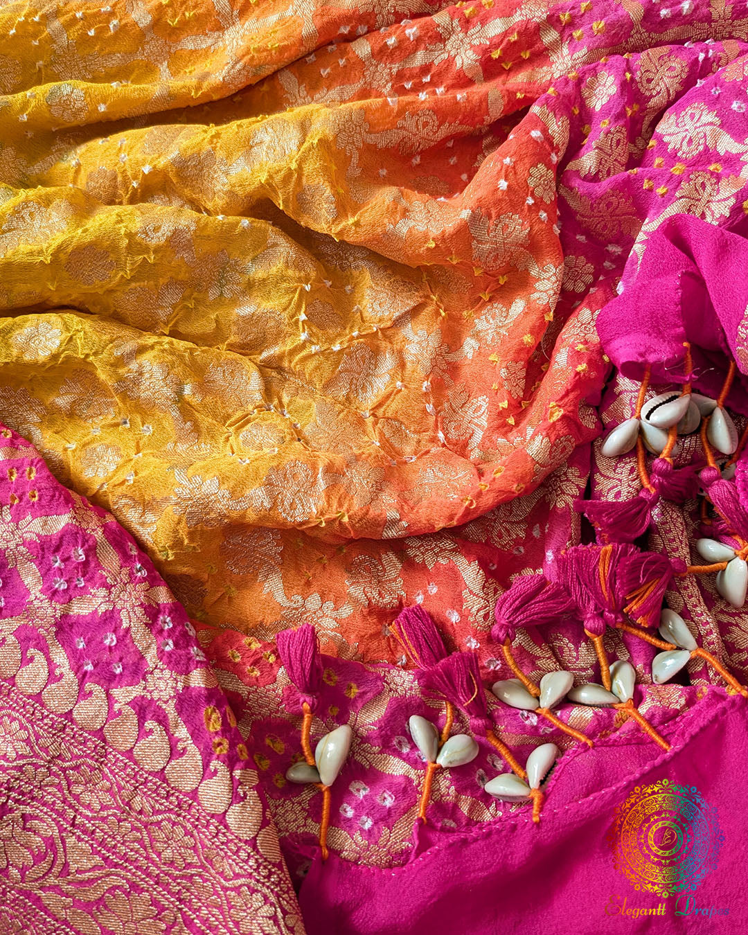 Close-up of traditional kodi tassels, zari border, and Bandhani motifs on pink orange shaded Banarasi georgette Gharchola Bandhani dupatta