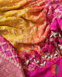 Close-up of traditional kodi tassels, zari border, and Bandhani motifs on pink orange shaded Banarasi georgette Gharchola Bandhani dupatta