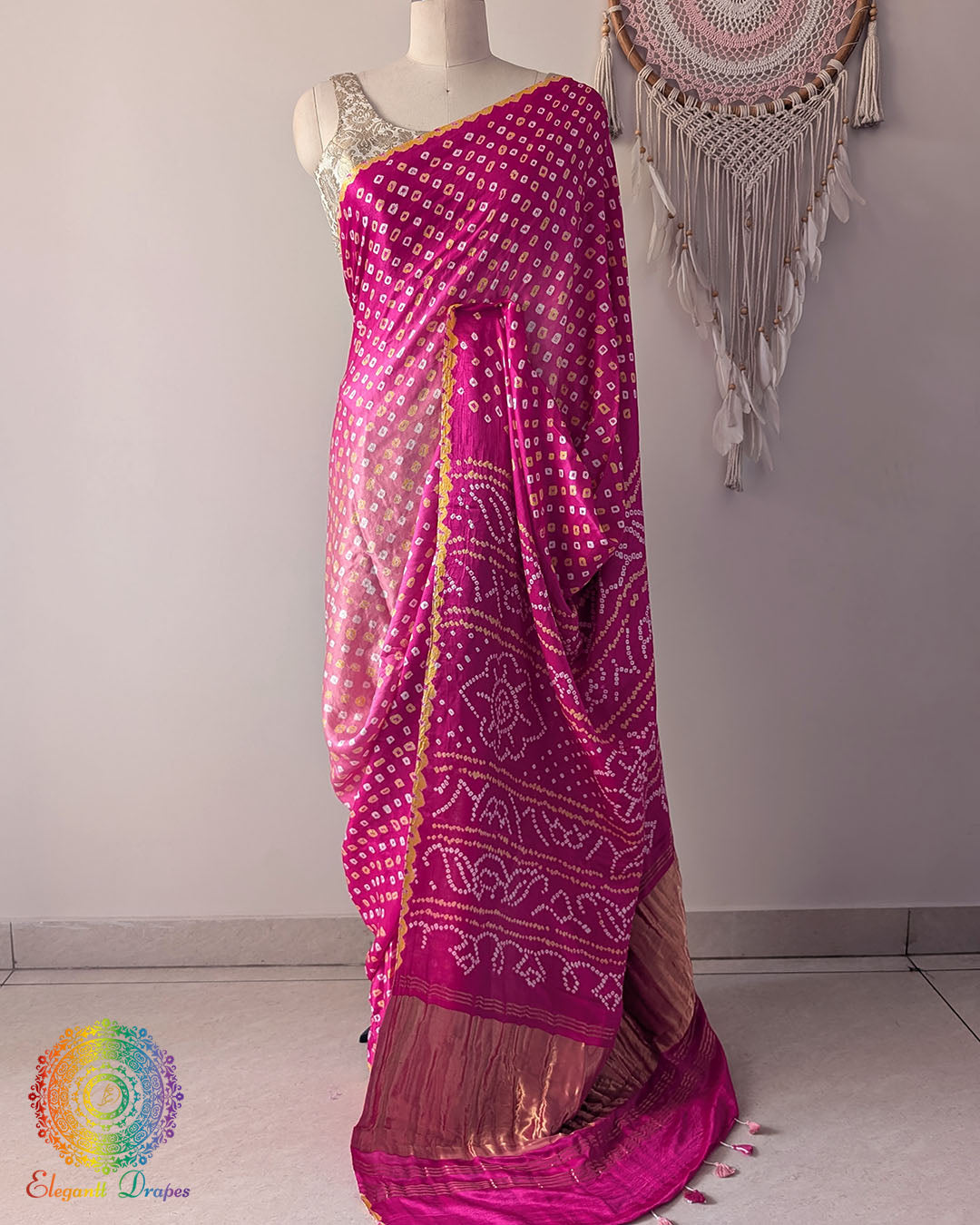 Pink shaded gaji silk saree on mannequin showcasing traditional bandhani dots
