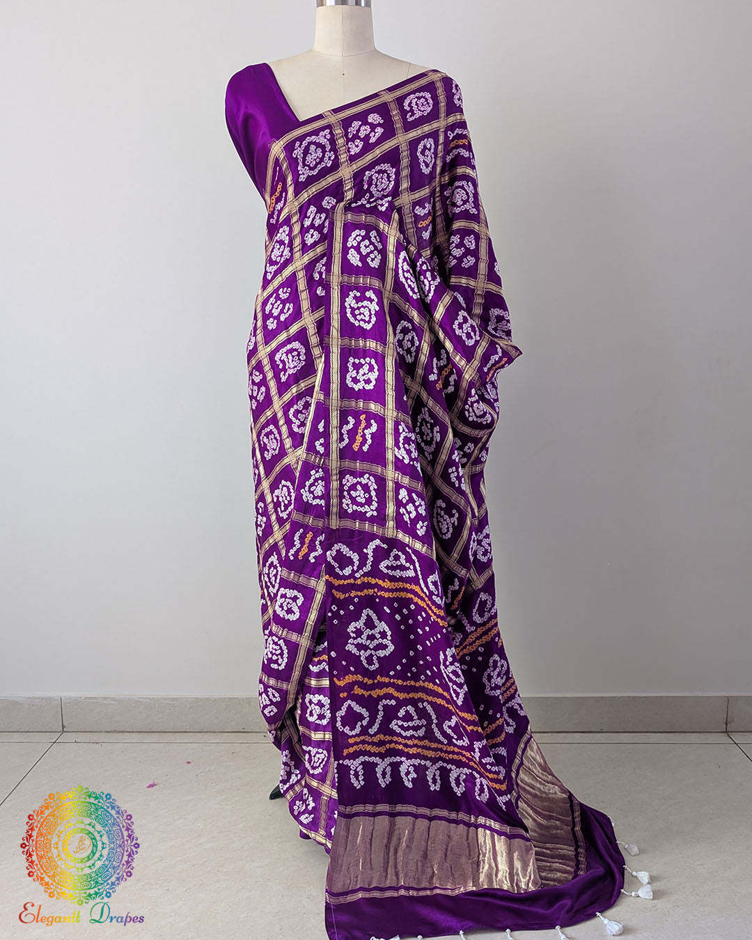 Violet Purple Pure Gaji Silk Bandhani Gharchola Saree with the palla visible in a draped view, displaying the white Bandhani motifs, gold-toned horizontal details and contrasting metallic border.