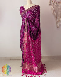 Pink palla on purple gaji silk saree highlighting Bandhani craftsmanship and Nakshi border