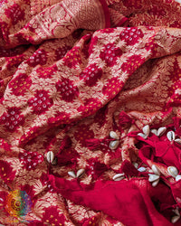 Close-up of traditional kodi tassels, zari border, and Bandhani motifs on bridal red Banarasi georgette Gharchola Bandhani dupatta
