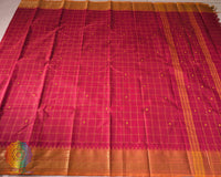 Full red Kanchi cotton checkered saree laid open showcasing orange border and overall design