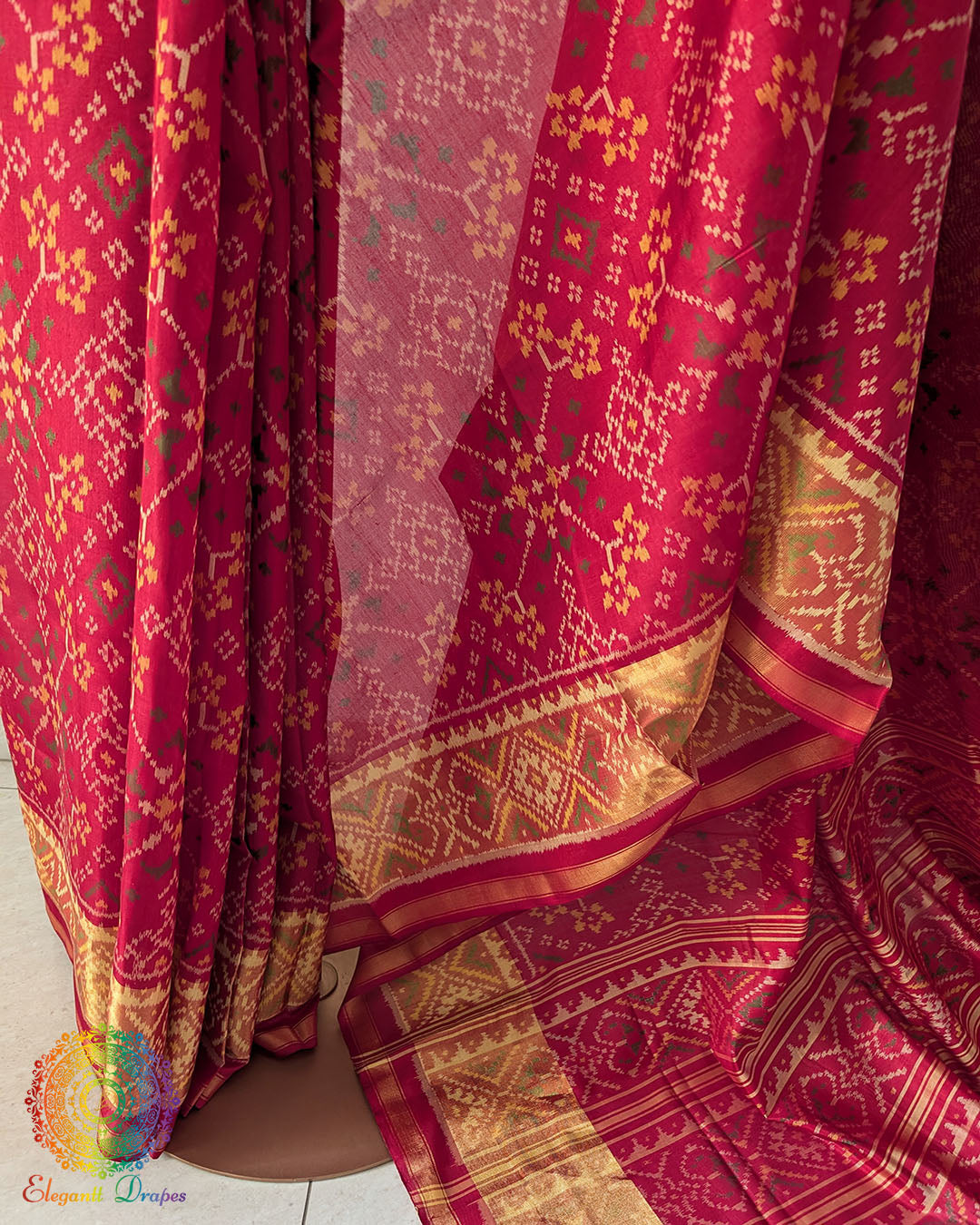 Pleats close up on traditional red Patola silk saree showcasing weave and pattern