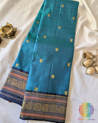 Teal Blue Pure Kanjivaram Handloom Silk Saree with 1gm Gold Zari displayed in a folded view, showcasing the rich teal blue silk and traditional golden zari detailing.