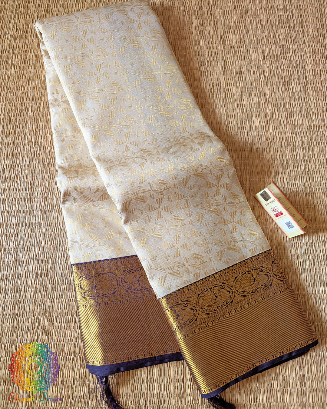Folded off white Kanjivaram silk saree showing golden zari weaving and blue border