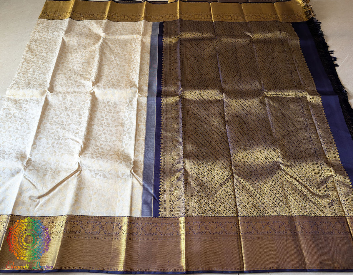 Full off white Kanjivaram silk saree laid open showing all-over golden zari motifs and blue palla