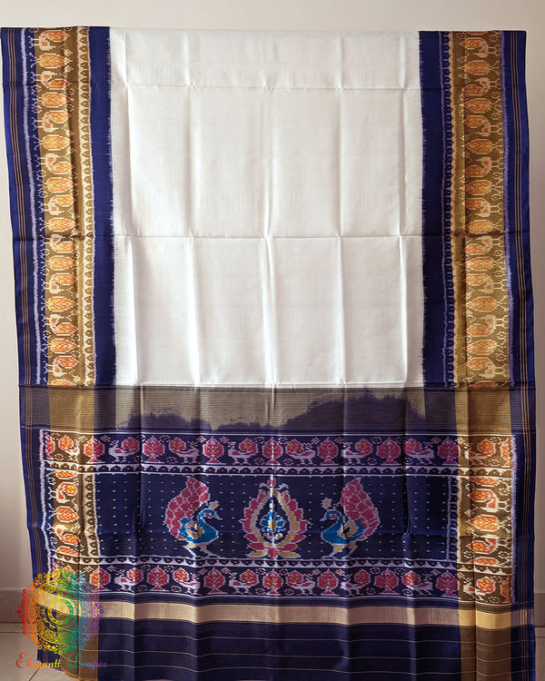 White Blue Handwoven Mulberry Silk Rajkot Patola Saree – Full Saree View displaying the complete saree with its white silk base, contrasting blue patterns and distinctive geometric designs inspired by traditional Rajkot Patola weaving.