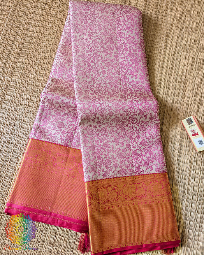 Folded white pink Kanjivaram silk saree showing pink thread weaving and zari detail