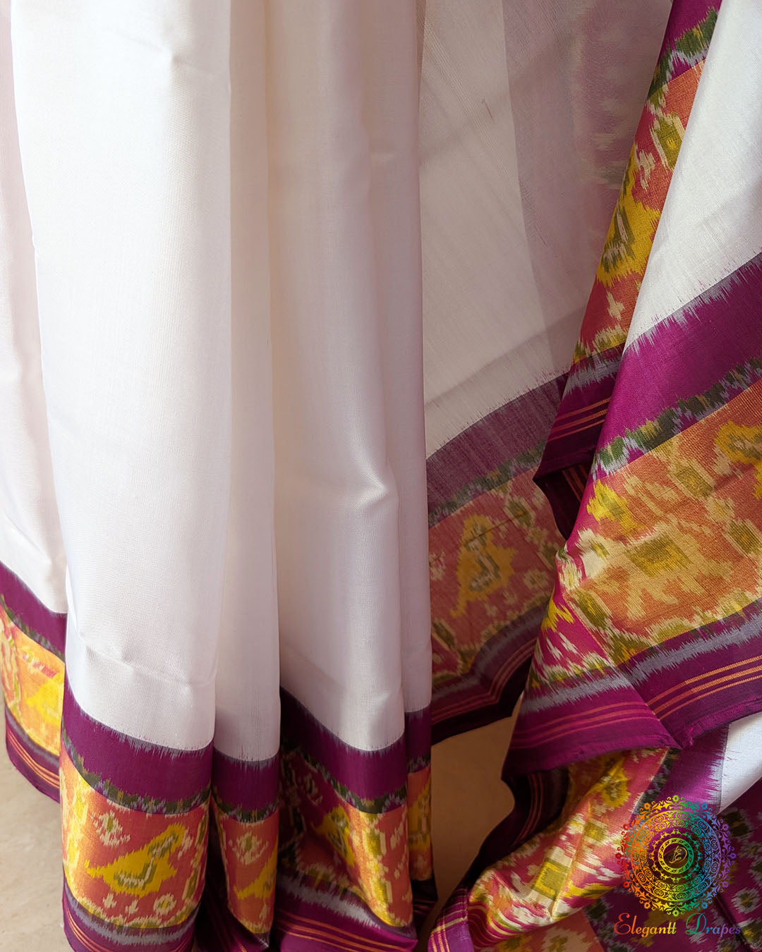 White Pink Rajkot Patola Saree – Pleats Detail View displaying the neatly arranged saree pleats, revealing the repeating Patola patterns, harmonious white and pink colours and the natural sheen of handwoven mulberry silk.
