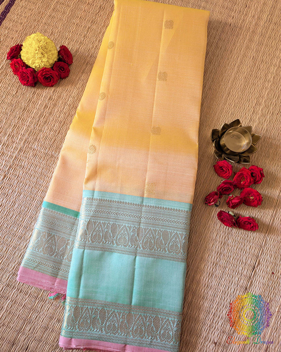 Yellow Pure Kanjivaram Handloom Silk Saree – Folded View showcasing the soft pale yellow silk body, delicate gold zari bootas and contrasting sea green border with traditional Kanjivaram weaving.